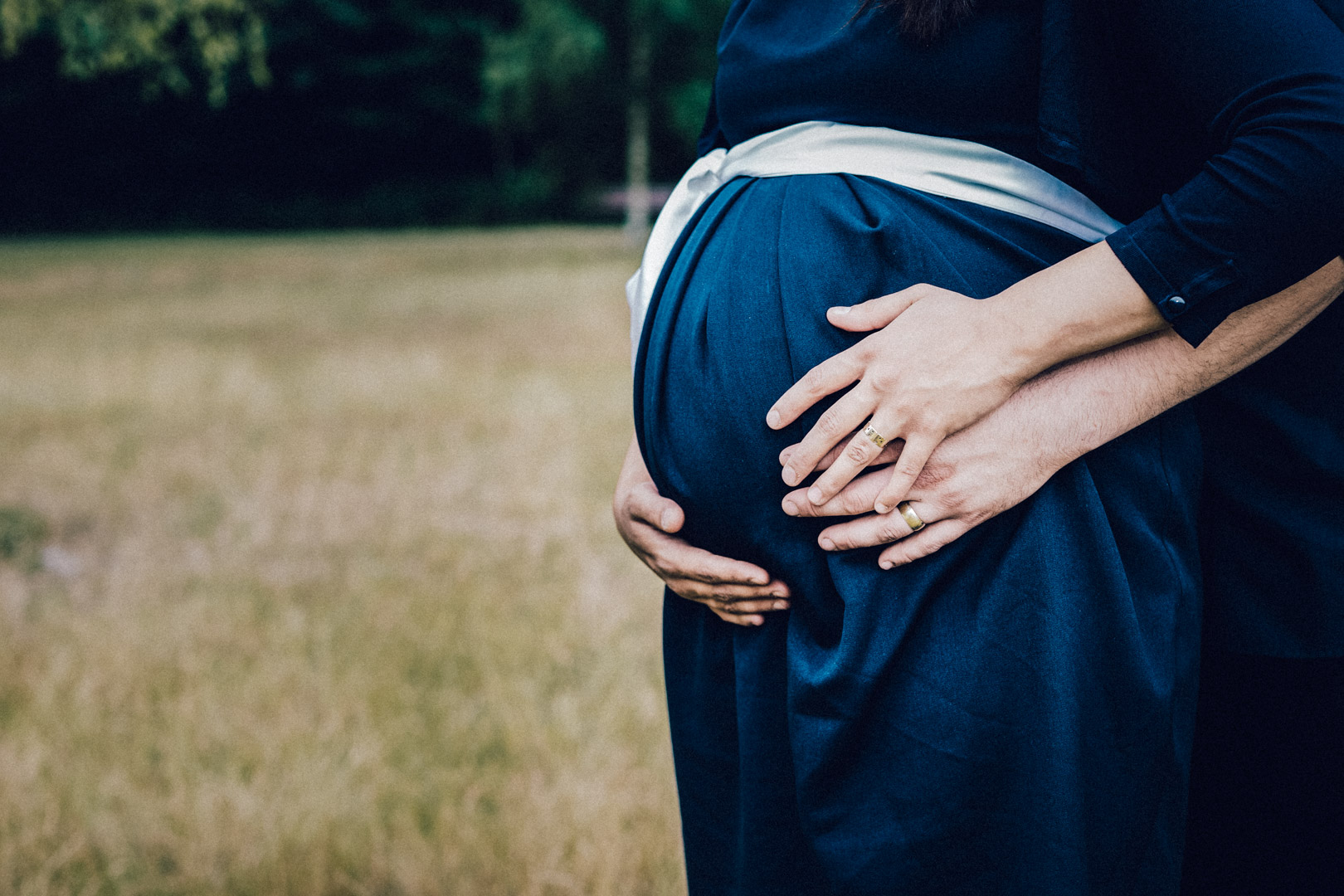 Familienfotograf Berlin Schwangerschaftsfotos: Babybauchfoto mit Händen der Eltern