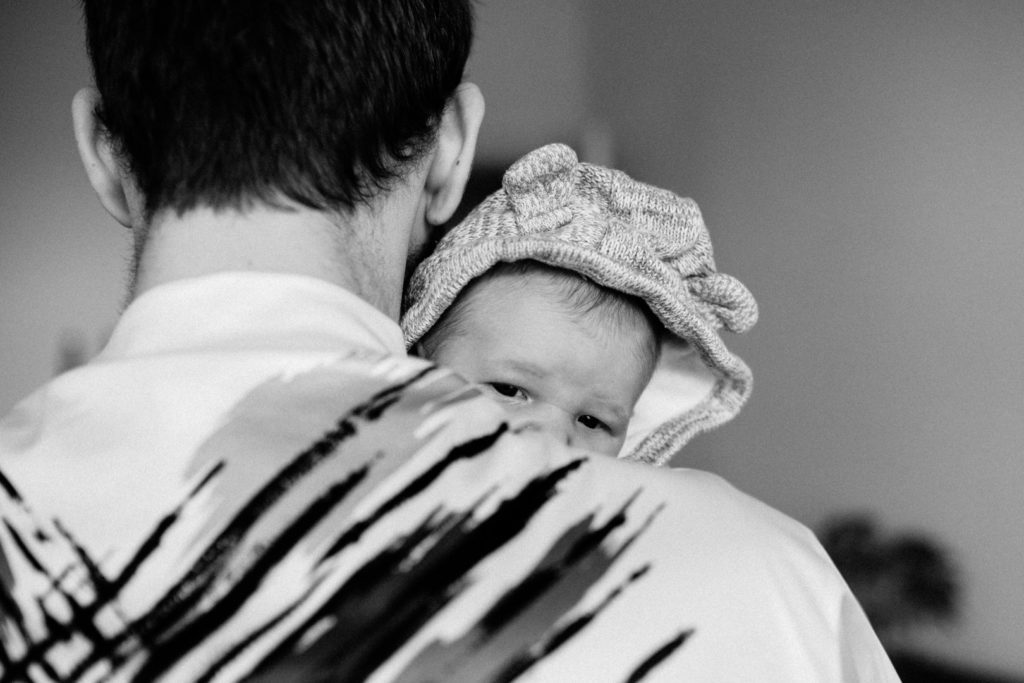 Neugeborenenfotos Berlin Familienreportage Berlin-Wedding: Baby schaut über die Schulter von Vater