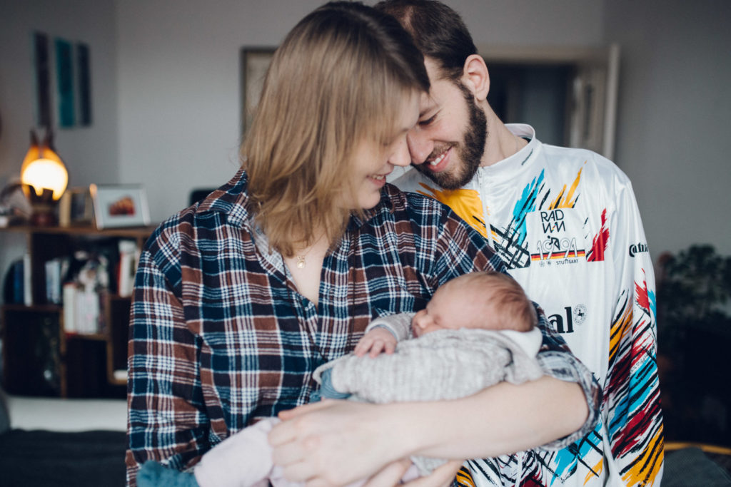 Lächelndes Paar mit Neugeborenem Baby bei Familienreportage in Berlin-Wedding. Neugeborenenfotos