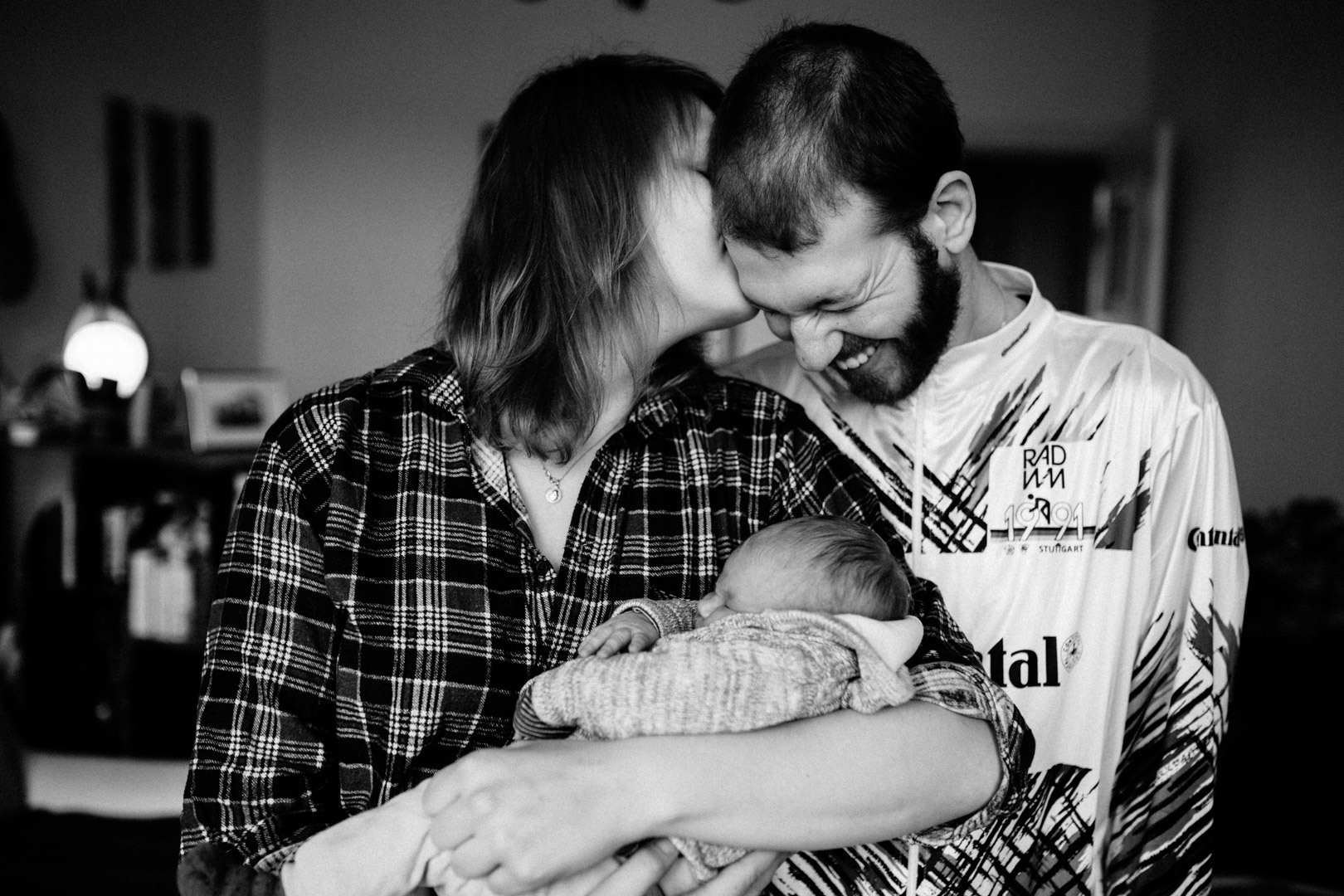 Neugeborenenfotos Berlin Familienreportage Berlin-Wedding: Frischgebackene Mama mit Baby auf dem Arm küsst Papa