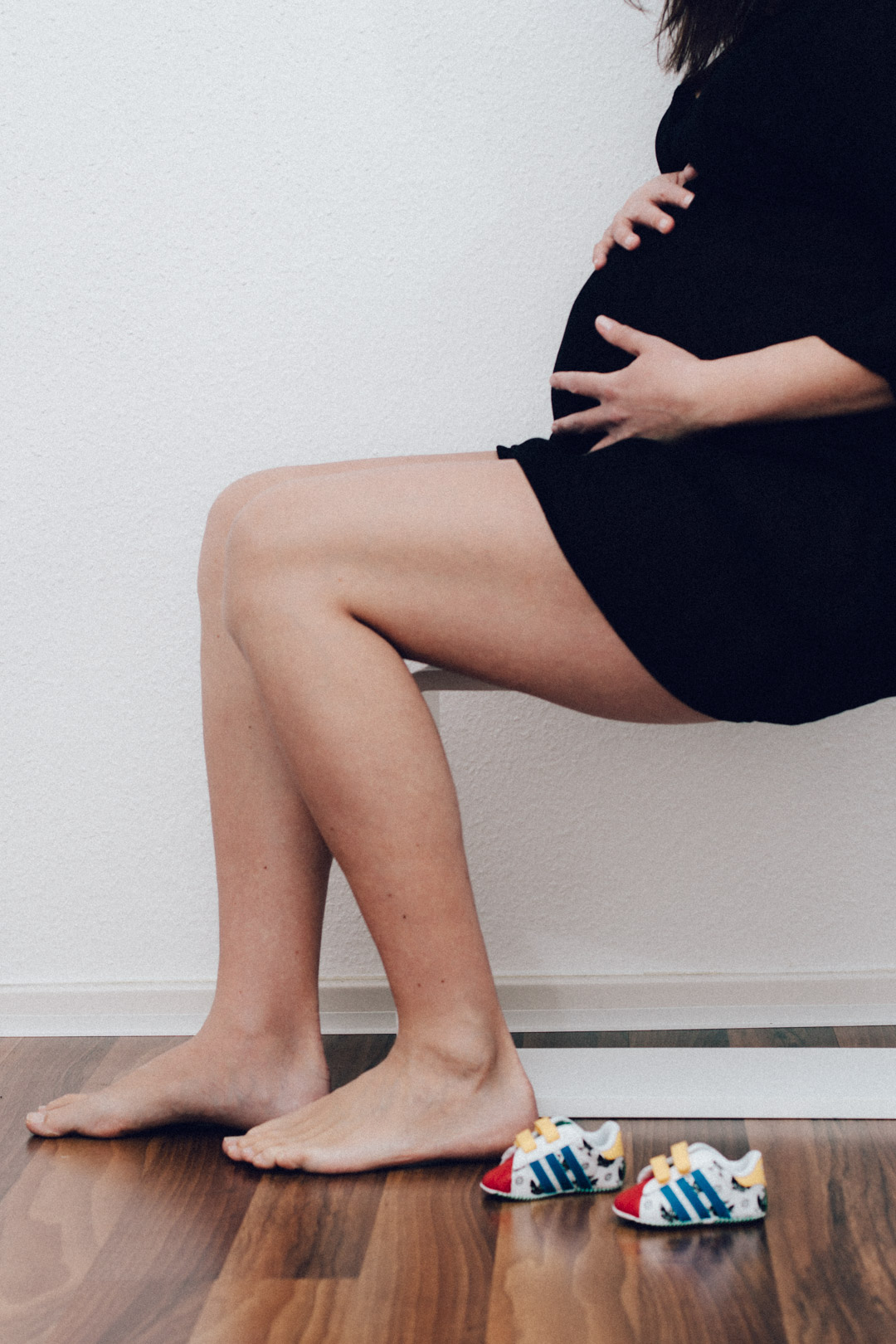 Familienfotograf Berlin Schwangerschaftsfotos: Babybauchfoto mit Babyschuhen im Vordergrund