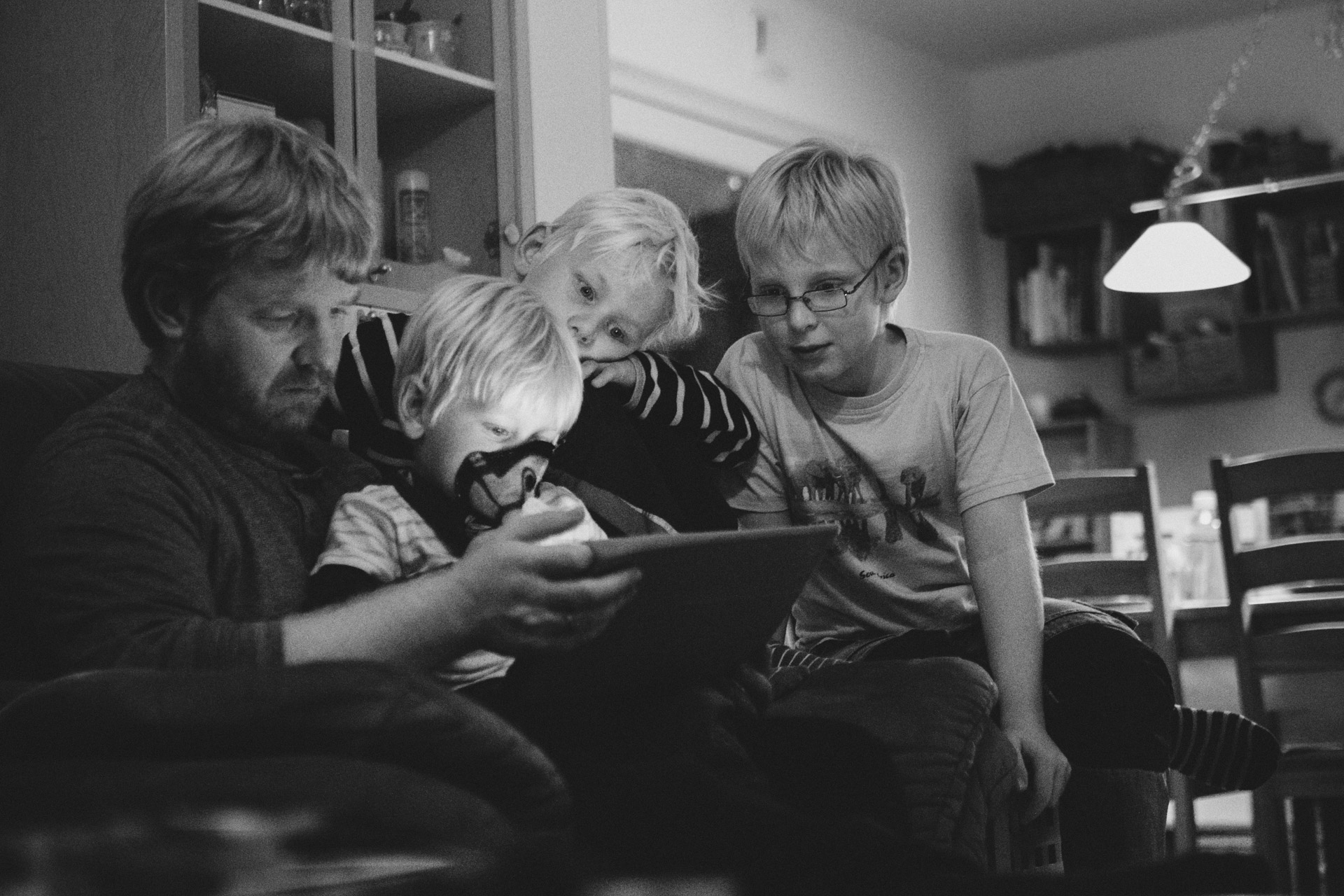 Vater sitzt mit 3 Kindern auf Sofa bei Familienreportage in Isenbüttel