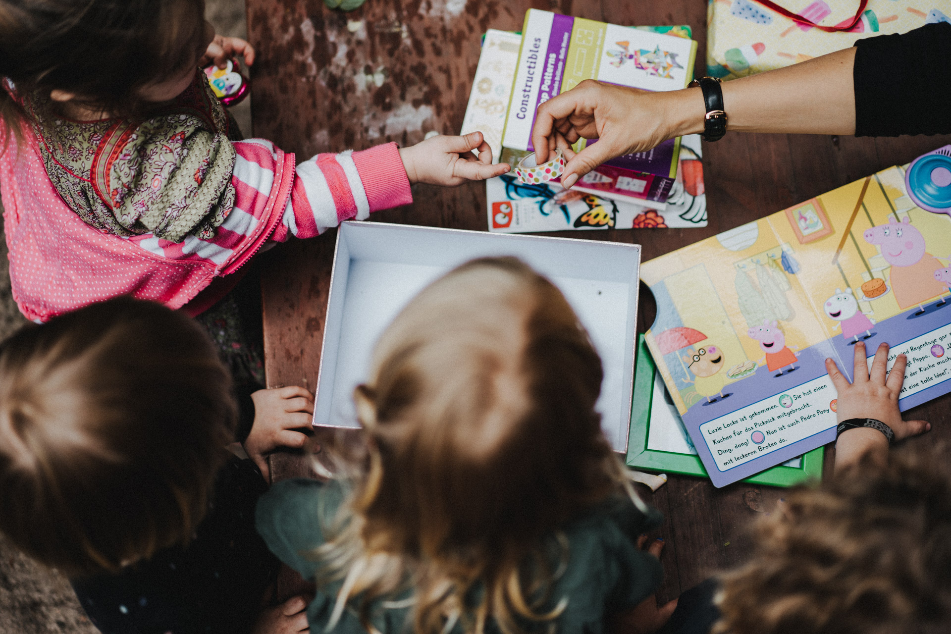 Familienreportage Berlin: Bild von oben: Kinder basteln. Kind streckt Hand nach Bastelmaterial aus