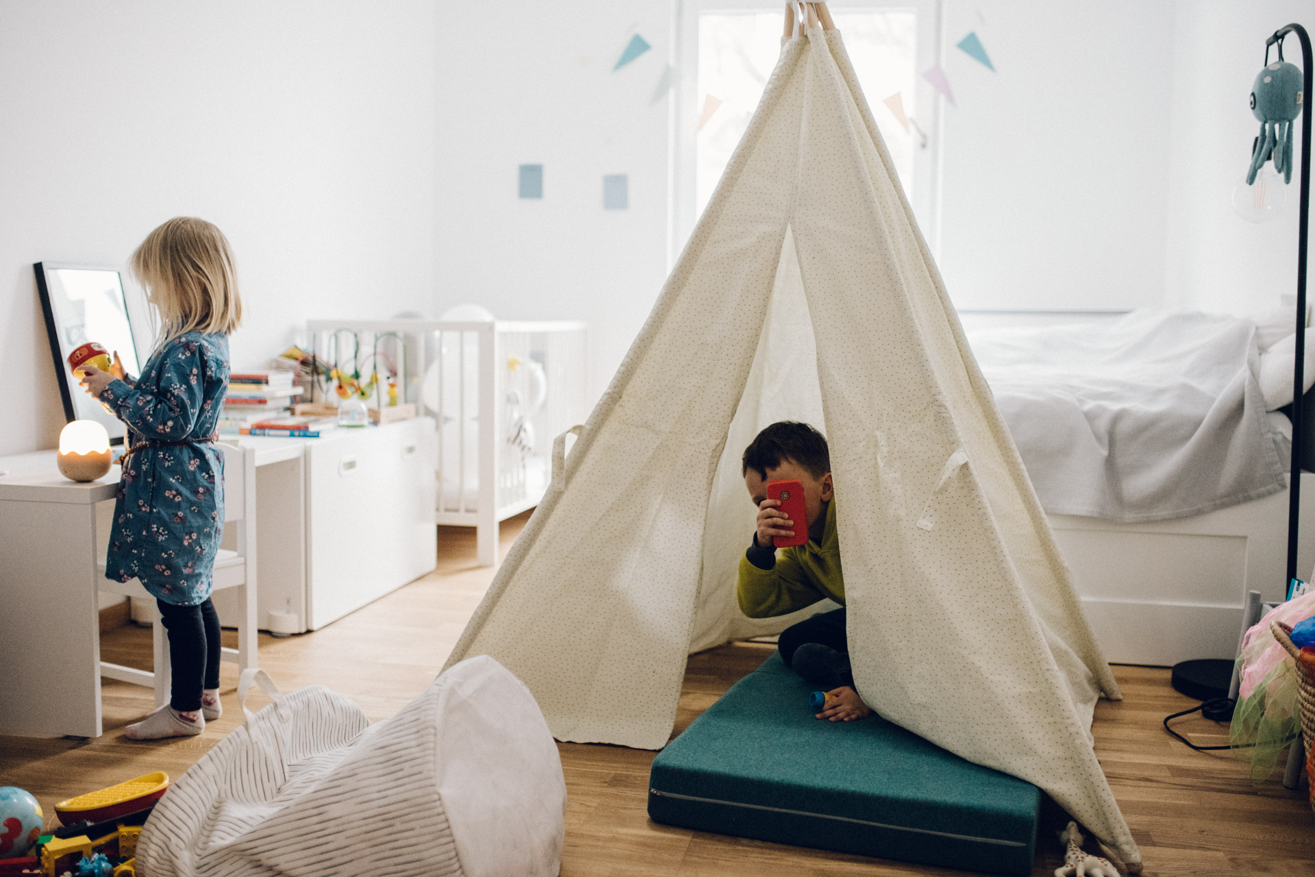 Familienreportage Berlin: zwei Kinder im Kinderzimmer. Mädchen steht an Tisch. Junge sitzt in Tipizelt