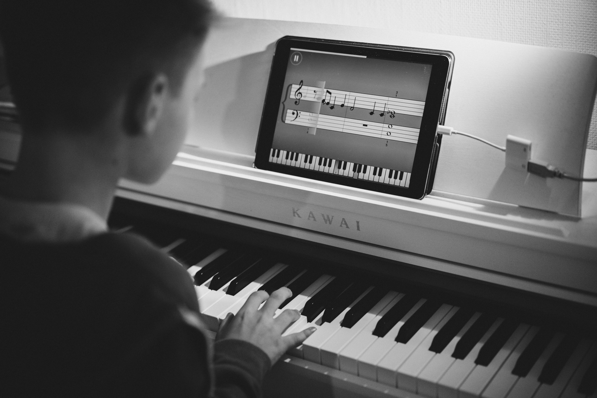 Familienreportage Berlin: Junge übt mit Hilfe eines Tablet Klavierspielen