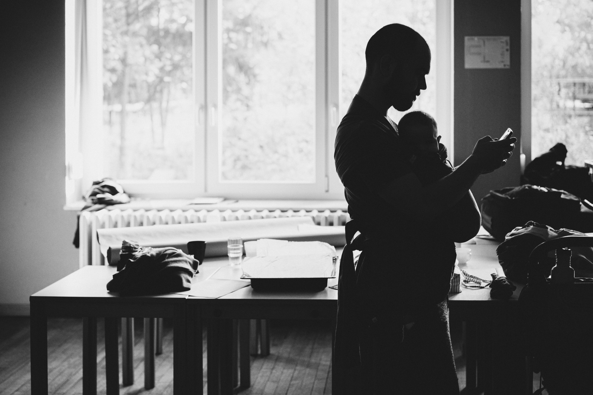 Silhouette von Vater mit Baby in Tragetuch bei Familienreportage in Hirschluch