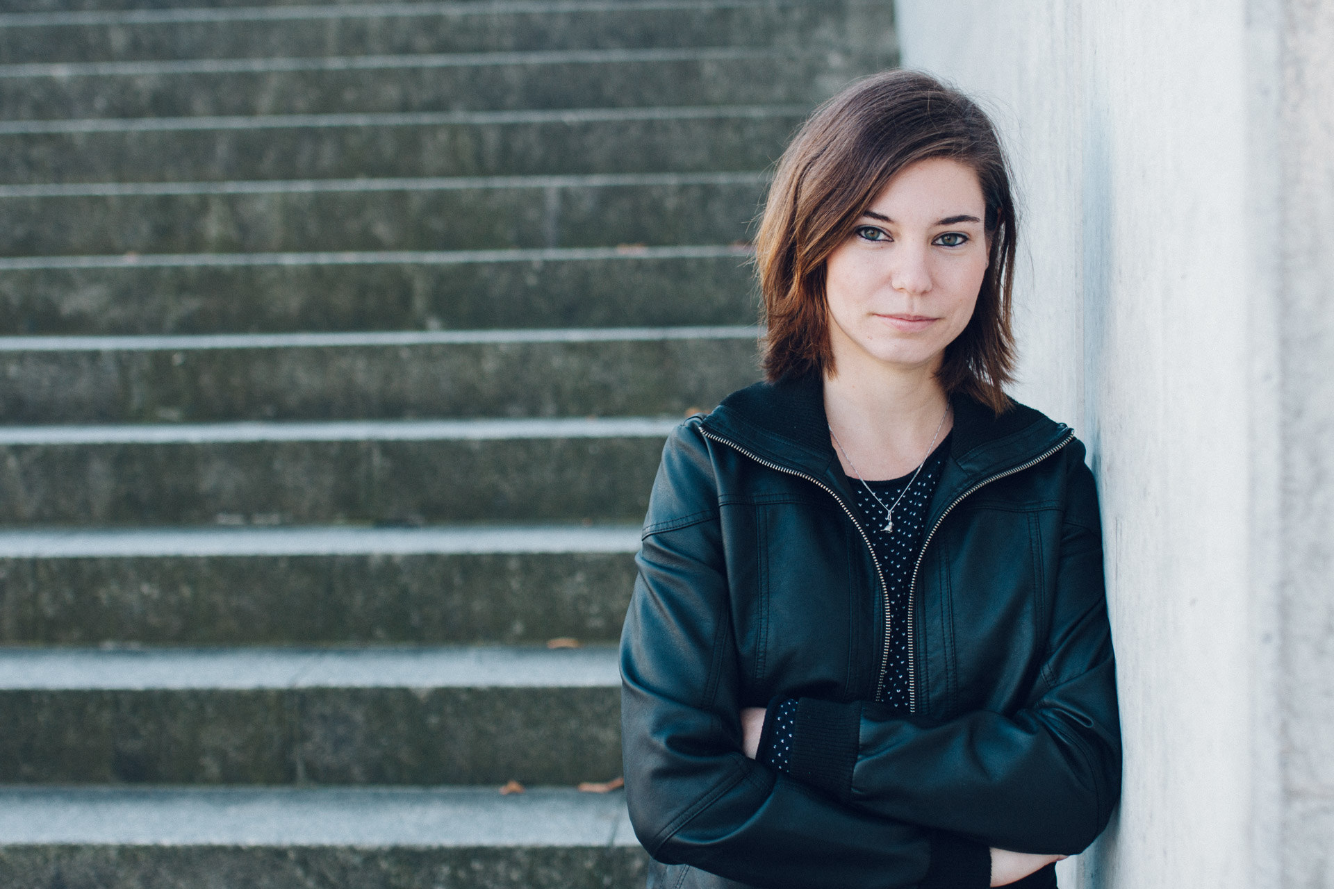 Portraits Berlin: Foto junge Frau mit verschränkten Armen an Wand gelehnt