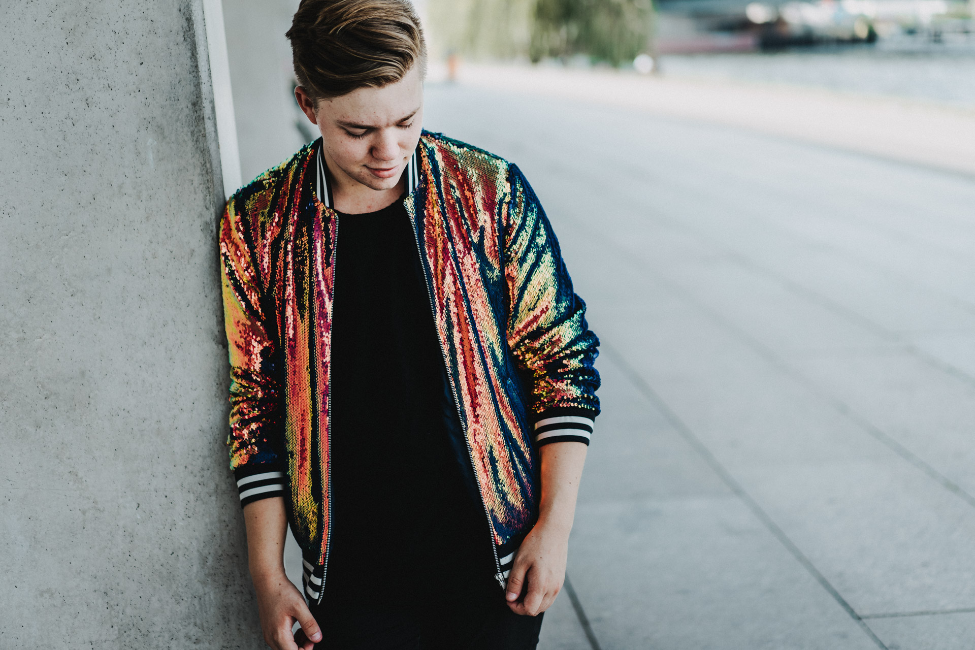 Portraits Berlin: DJ Paul Palette in glitzernder Jacke vor grauer Wand